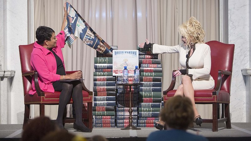 Librarian of Congress Carla Hayden (left) and Dolly Parton unveil “Coat of Many Colors,” the book Parton donated to the Library this week